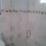 ALL MARBLE SHOWER WITH ACCENT STRIP. CUSTOM GLASS ENCLOSER WITH PIVOT DOOR.